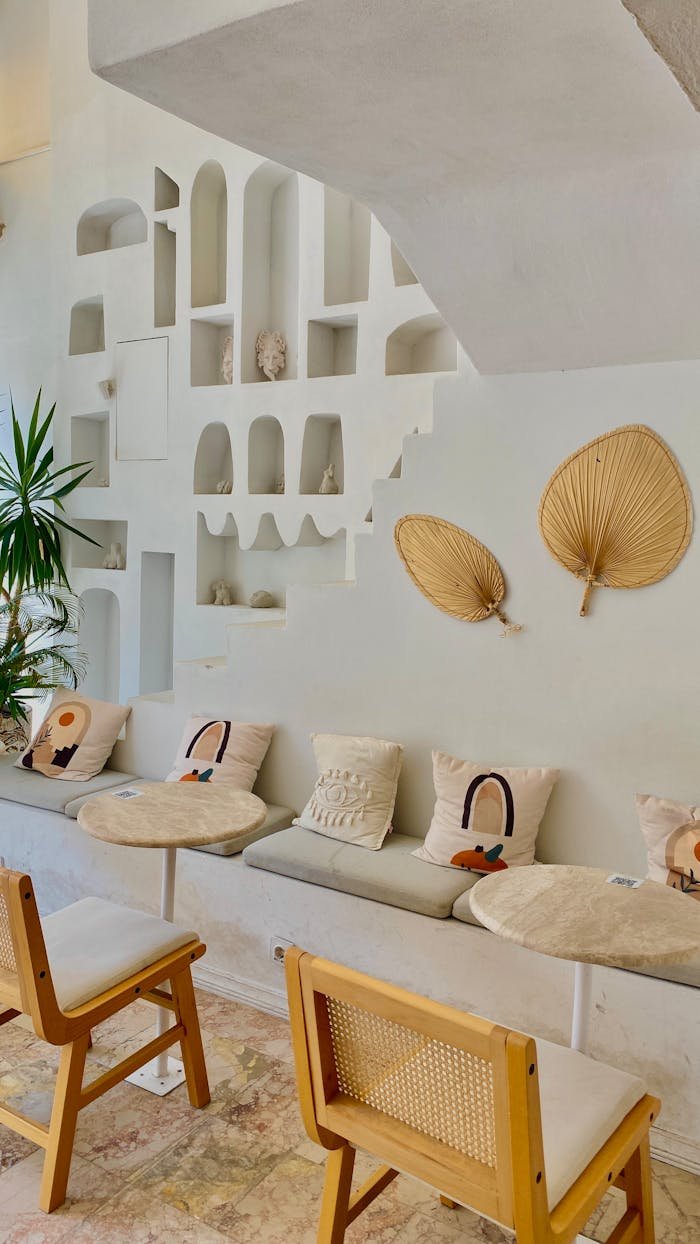 Modern cafe interior featuring boho decor elements with beige palette, wooden chairs, and chic wall art.
